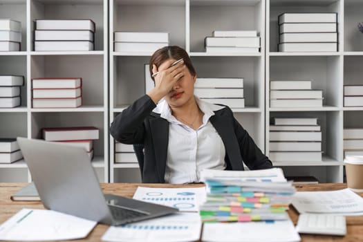 Asian business women are stressed while working on laptop and pile of documents, Tired asian businesswoman with headache at office, feeling sick at work.