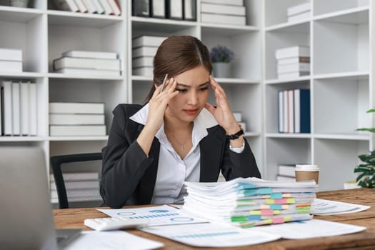 Asian business women are stressed while working on laptop and pile of documents, Tired asian businesswoman with headache at office, feeling sick at work.