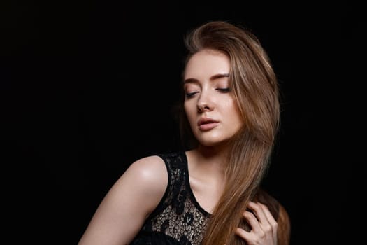 gorgeous brunette woman with long hair in black dress on black background. copy space