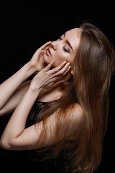 gorgeous sexy brunette woman with long hair in black dress on black background