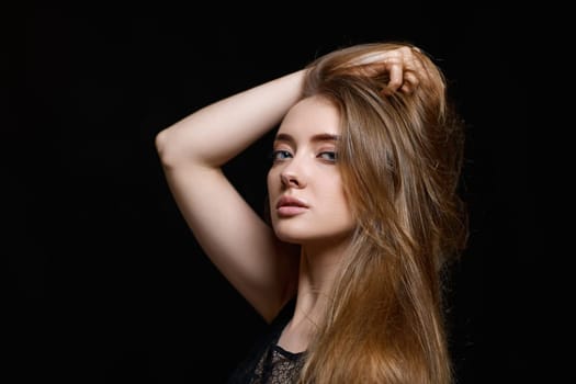 gorgeous brunette woman with long hair in black dress on black background. copy space