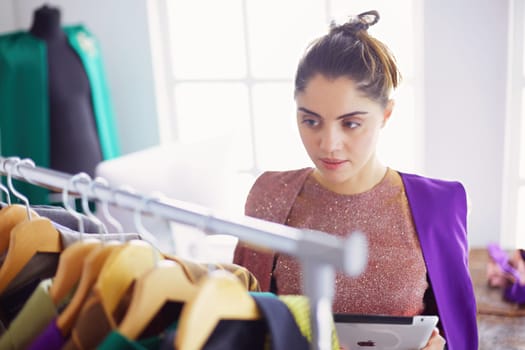 Beautiful young stylist near rack with hangers.