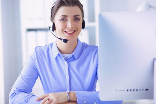 Serious pretty young woman working as support phone operator with headset in office.