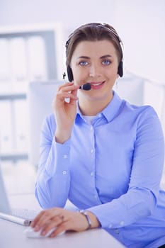 Serious pretty young woman working as support phone operator with headset in office.