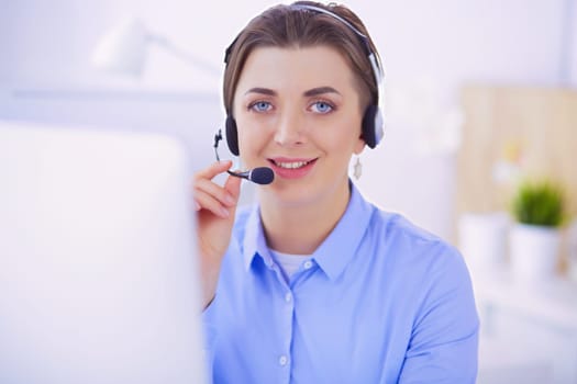 Serious pretty young woman working as support phone operator with headset in office.