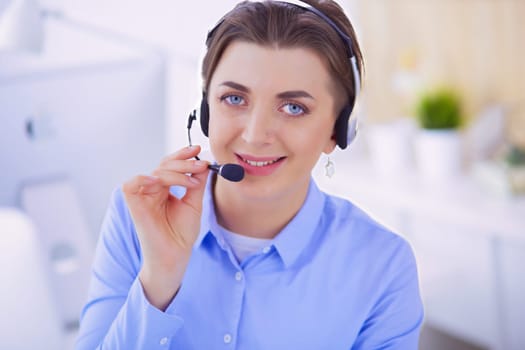 Serious pretty young woman working as support phone operator with headset in office.