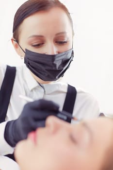 Cosmetologist applying permanent make up on eyebrows.