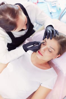 Cosmetologist applying permanent make up on eyebrows.