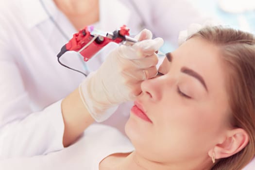 A young girl having red lips permanent makeup, micropigmentation.