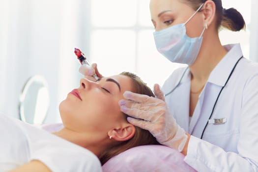 A young girl having red lips permanent makeup, micropigmentation.