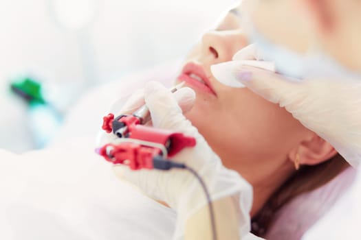 A young girl having red lips permanent makeup, micropigmentation.