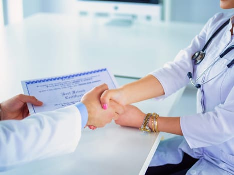 Doctor shakes hands with a patient isolated on white background.