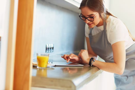 Portrait of young attractive caucasian brunette housewife at kitchen. Morning with cup of coffee and tablet pc.