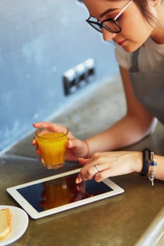 Attractive woman holding a glass of orange juice while standing in the kitchen.
