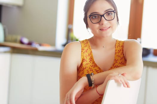 Young woman sitting a table in the kitchen .