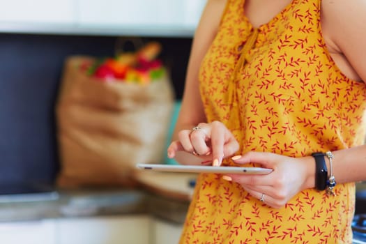 beautiful young woman using a digital tablet in the kitchen.