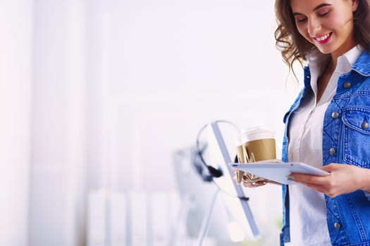 Smiling woman drinking coffee and using tablet in the cafe
