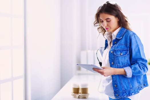 Smiling woman drinking coffee and using tablet in the cafe