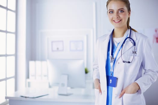 Portrait of young woman doctor with white coat standing in hospital.