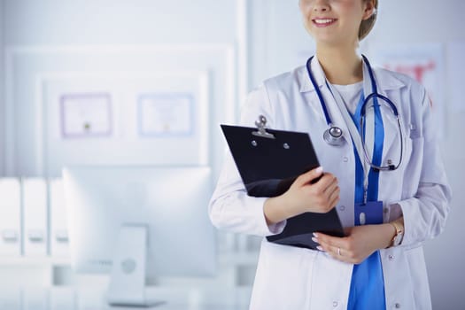 Smiling female doctor with a folder in uniform standing.