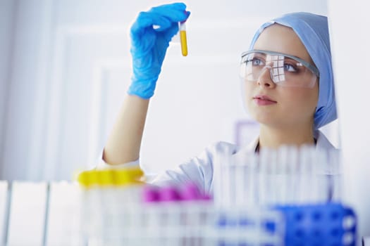 A female medical or scientific researcher or woman doctor looking at a test tube of clear solution in a laboratory .