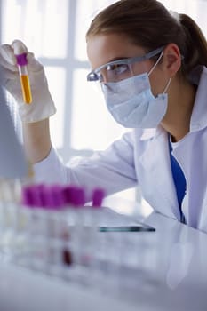 Woman researcher is surrounded by medical vials and flasks, isolated on white.
