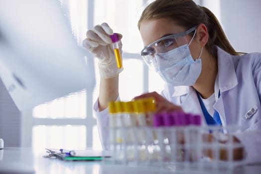 Portrait of pretty female laboratory assistant analyzing a blood sample at hospital .