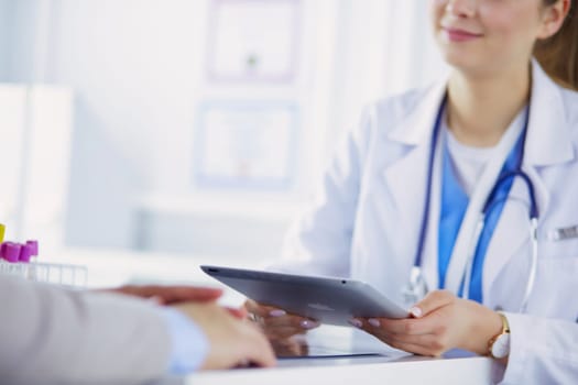 Female doctor using tablet computer in hospital lobby, smiling.