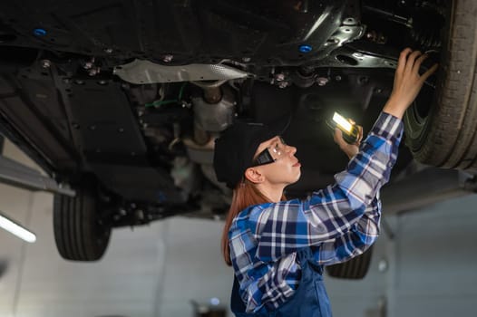 A female mechanic inspects a lifted car. A girl at a man's work