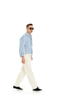Smiling happy confident man in sunglasses and blue striped shirt standing isolated on white background. full length. Summer fashion