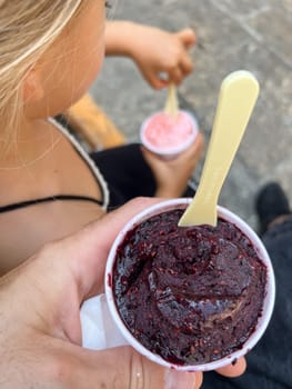 Cup of popsicles in dad hands near little girl eating ice cream. High quality photo