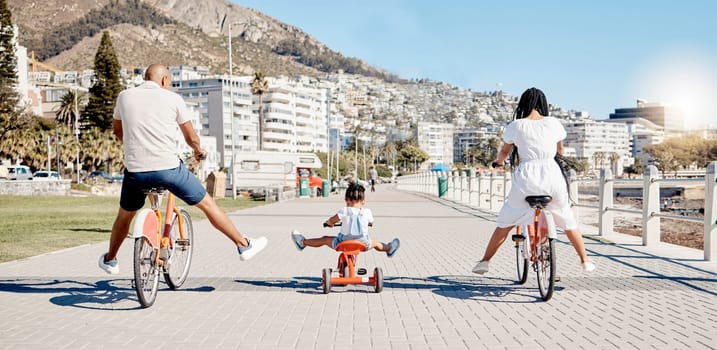 Black family, bike and children with a girl and parents having fun together on the promenade in summer. Freedom, bicycle and kids with a mother, father and daughter riding while bonding from the back.