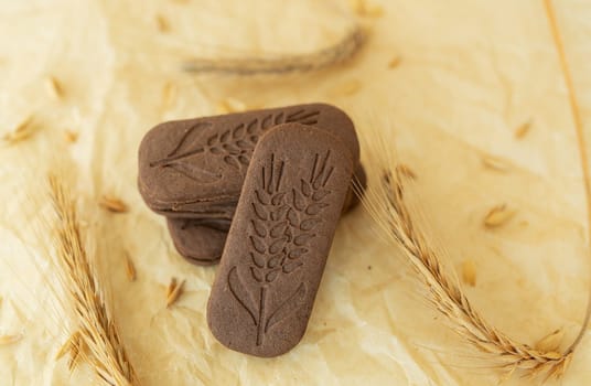 Close-up of a chocolate chip cookie imprinted with a branch of wheat on parchment