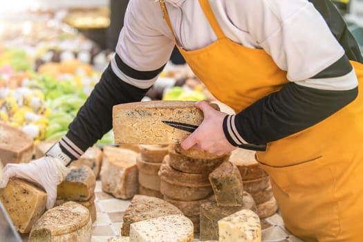 A man gives a cheese tasting to his customer. Cheese tasting. Cheese is cut with a special cheese knife. High quality photo