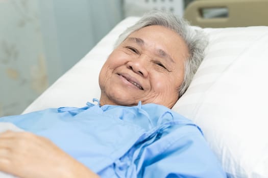 Asian elderly woman patient smile bright face with strong health while lying on bed in hospital, healthy strong medical concept.