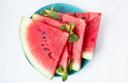 Fresh ripe slices of watermelon along with mint leaves lie on a plate on the table. Tasty and healthy, summer food