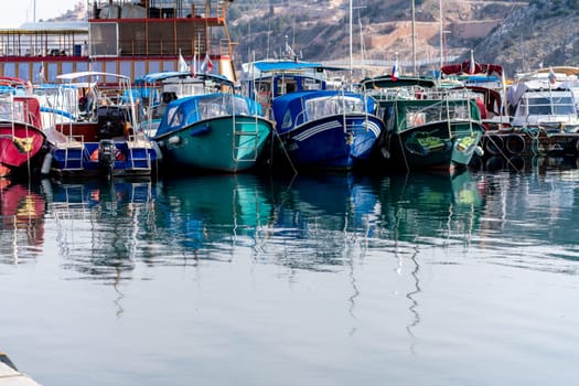 Reflection in the sea surface of white yachts parked in the port on the shore. Fragment of a ship on the water and the reflection of ships in the sea. motionless mirrored water of the sea.