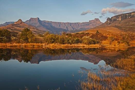 Early morning reflections of the Amphitheater formation in a calm Drakensberg lake in Royal Natal National Park. KwaZulu-Natal. South Africa