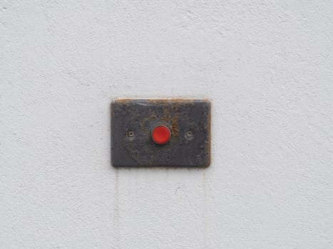 Red old alarm button on the white cement wall. Service accessible entrance sign. Help call button for people.