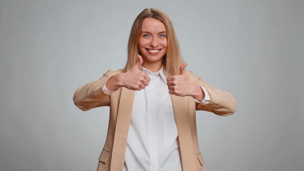 Like. Portrait of secretary woman in suit raises thumbs up agrees with something or gives positive reply recommends advertisement likes good. Business girl isolated alone on gray studio background