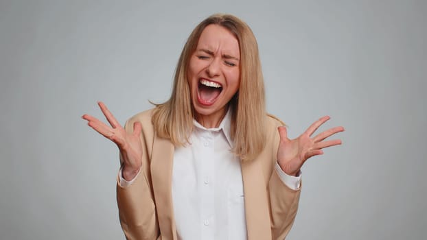 Sad woman in suit screams yell from stress tension problems feels horror hopelessness fear panic surprise shock expresses gestures rage. Business freelancer girl isolated on gray studio background