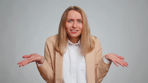 What Why. Sincere irritated business woman raising hands in indignant expression asking reason of failure demonstrating disbelief irritation by trouble. Confused girl in formal suit on gray background