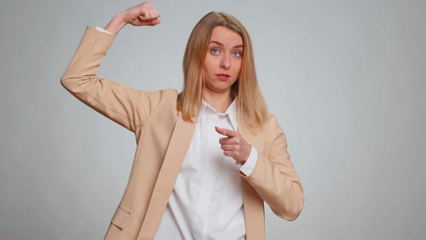 I am strong and independent. Business woman showing biceps and looking confident, feeling power strength to fight for rights, energy to gain success win. Entrepreneur girl on gray studio background