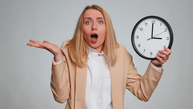 Portrait of young business woman with anxiety checking time on clock, running late to work, being in delay, deadline. Female girl in formal suit looking at hour, minutes, worrying to be punctual