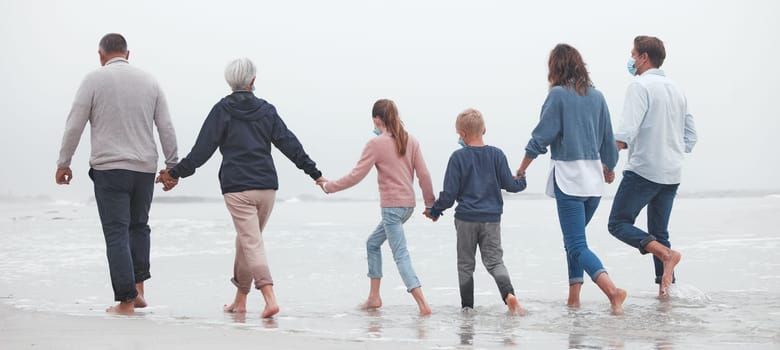 Big family, holding hands and walking on beach for vacation or quality bonding time together in nature. Hand of parents, grandparents and kids enjoying travel, freedom and family fun in ocean water.