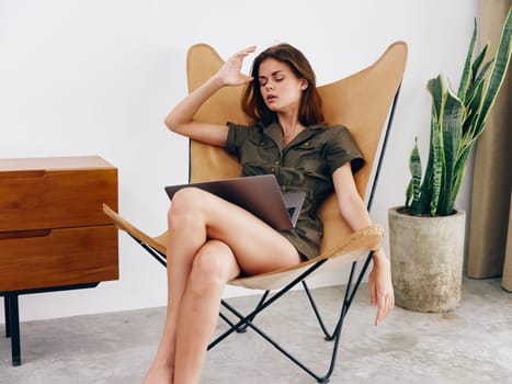 Female freelancer sitting in a chair with a laptop work at home sadness dissatisfaction tiredness, modern stylish interior Scandinavian lifestyle, copy space. High quality photo