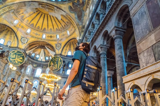 Man tourist enjoying Hagia Sofia, Ayasofya interior in Istanbul, Turkey, Byzantine architecture, city landmark and architectural world wonder. Turkiye.
