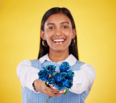 Portrait, love and roses with a woman on a yellow background in studio for valentines day. Face, blue flowers or smile with a happy young female holding a plant for romance or anniversary celebration.