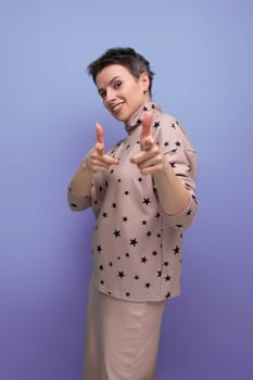 young pretty woman with childlike features with a short haircut is dressed in a beige suit.