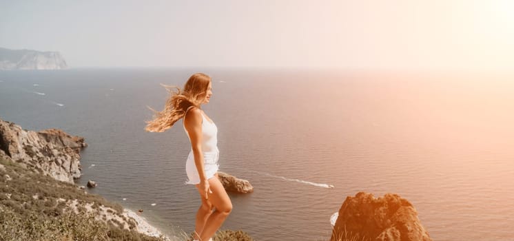 Woman travel sea. Young Happy woman in a long red dress posing on a beach near the sea on background of volcanic rocks, like in Iceland, sharing travel adventure journey